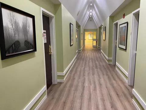 Hallway with pale green walls, wood-look flooring and framed prints