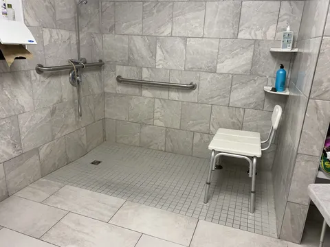 Tiled shower with grab bars, shower head and shower chair