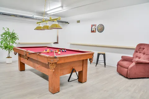 Billiards room with a red pool table, dartboard and pink reclining chair