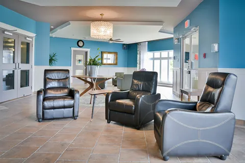 Room with black reclining armchairs, blue walls, a round table and large windows