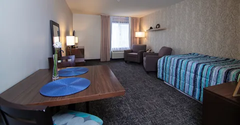 Room with a bed, dining table, chairs and two armchairs