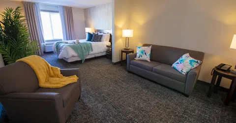 Suite with a bed, sofa, armchair, lamps and a large window