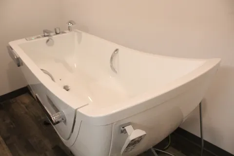 White accessible bathtub with grab rails and a handheld shower