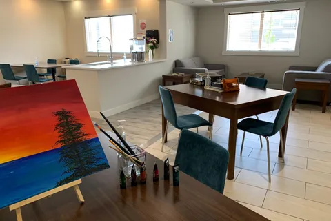 Room with tables, teal chairs, a counter and a painting on an easel