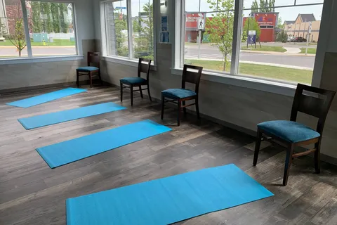 Room with exercise mats and chairs beside large windows