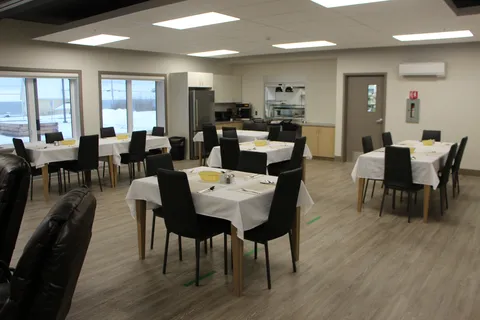 Dining area with white tablecloths, black chairs and a serving hatch