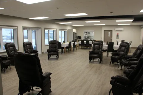 Room with black armchairs, large windows and dining tables