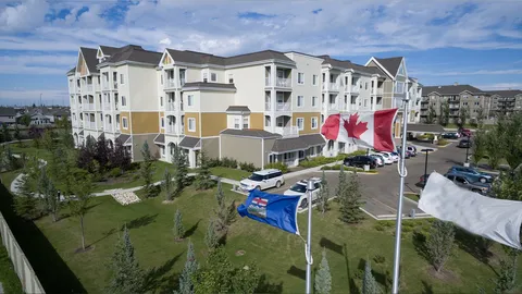 Building exterior with balconies, parked cars and flags