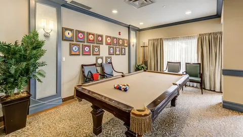 Room with a pool table, chairs and framed billiard ball pictures