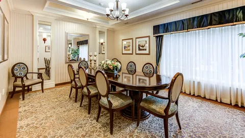 Dining room with an oval table, upholstered chairs and curtained windows