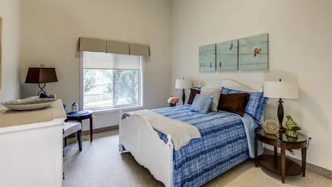Bedroom with a blue bedspread, bedside tables and a window