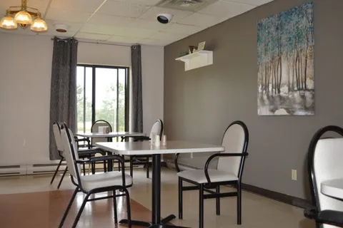 Dining tables beside a window and a large tree painting