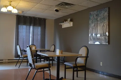 Dining table with upholstered chairs and a tree painting on the wall