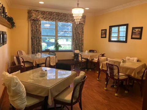 Dining tables and chairs beside large windows and a wall mirror