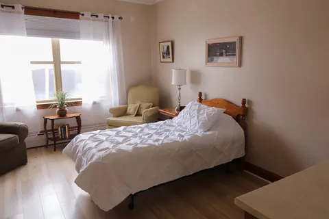 Bedroom with a white bed, wooden furniture and a window