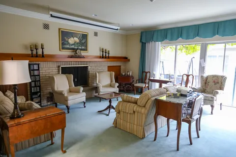 Room with armchairs, a sofa and a fireplace beneath a flower painting