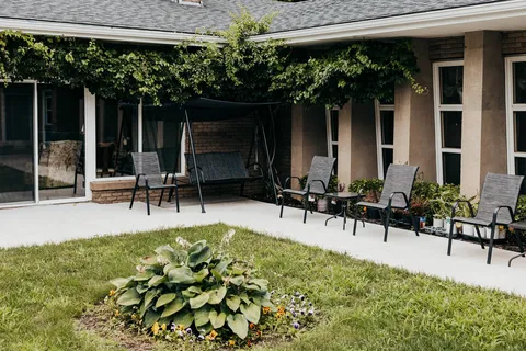 Garden seating and a canopy swing beside the rear of a brick building