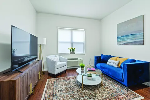 Sitting area with a blue sofa, white armchair and television