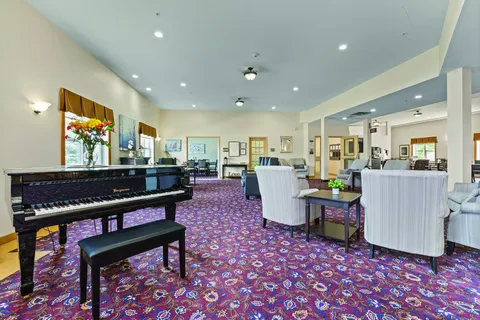 Room with a grand piano and upholstered seating on a patterned carpet