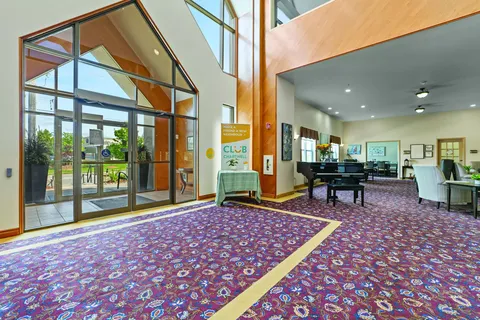 Tall-windowed room with a piano, seating and glass exterior doors