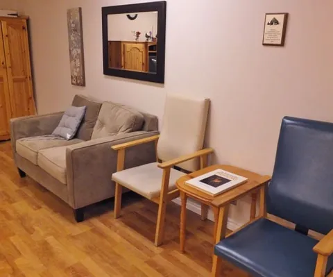 Sofa and chairs beside a wooden side table and wall mirror.