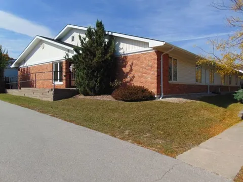 Single-storey brick residence with white gables and a roadside lawn.