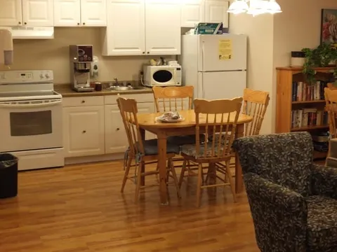Suite kitchen with white cabinets and a wooden dining table.