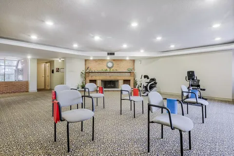 Carpeted exercise room with chairs, exercise bands and fitness equipment