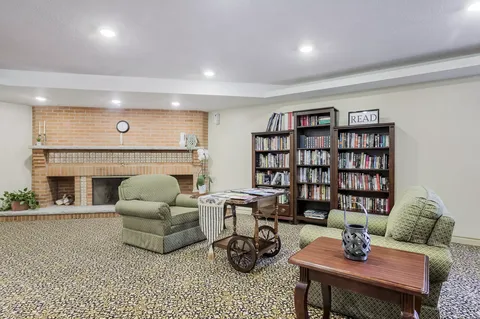 Room with armchairs, bookcases and a brick fireplace