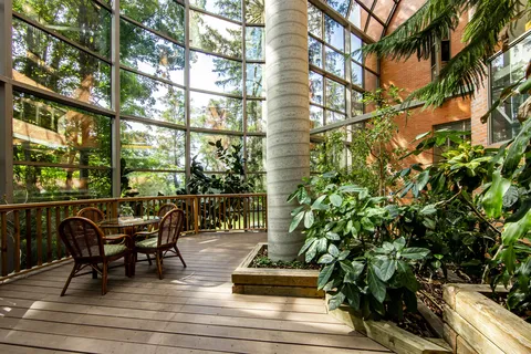Glass-roofed atrium with chairs, tables and lush planting