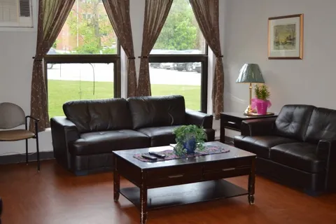 Black sofas and a coffee table beside tall windows