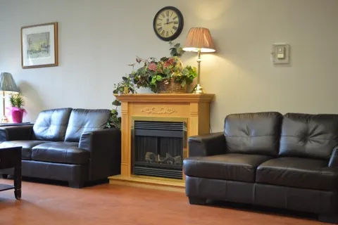 Black sofas beside a fireplace topped with a flower arrangement