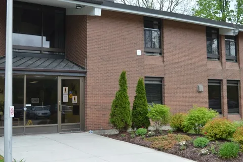 Two-storey brick residence with a glass entrance and shrubs
