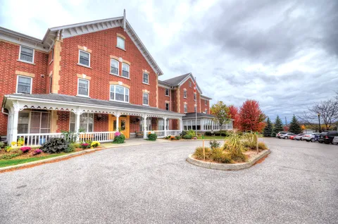 Red-brick Champlain Manor building with a covered porch and circular driveway.