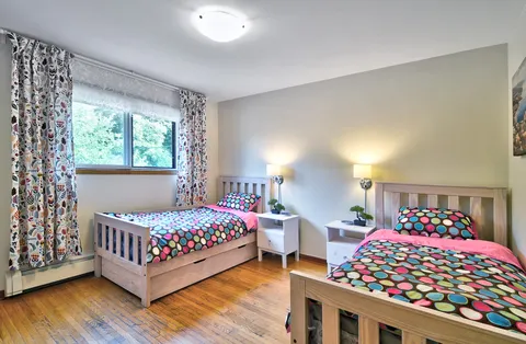 Bedroom with two single beds, patterned bedding and a wide window
