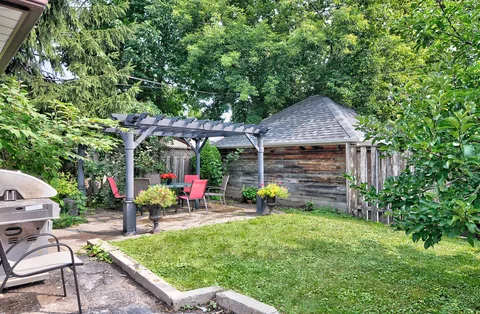 Garden lawn beside a pergola, red patio chairs and a wooden shed
