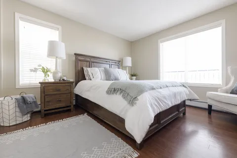 Bedroom with a large bed, wood bedside tables and bright windows