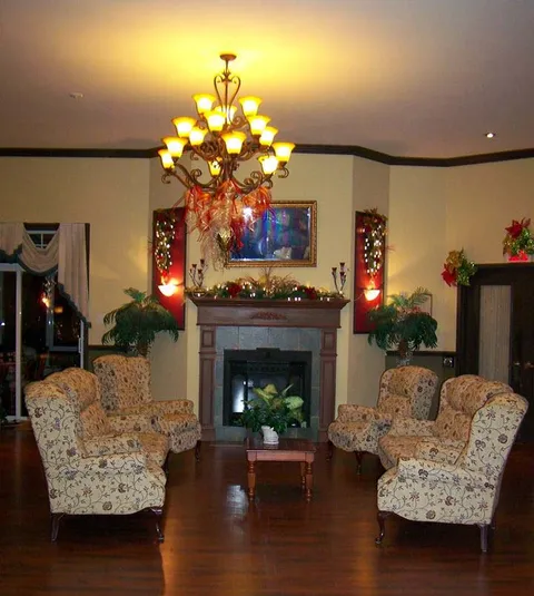 Sitting room with armchairs, a fireplace and chandelier.