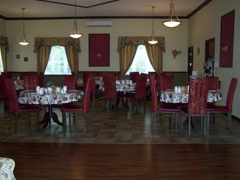 Dining room with tables, chairs, wood flooring and windows.