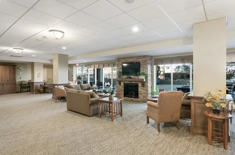 Common room with sofas, armchairs and a television above a stone fireplace