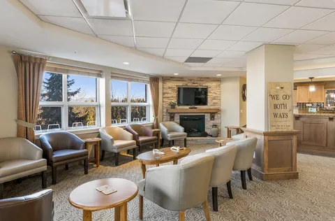 Armchairs arranged beside a stone fireplace and broad windows