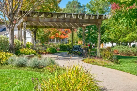 Garden with a pergola, picnic tables and planted beds.