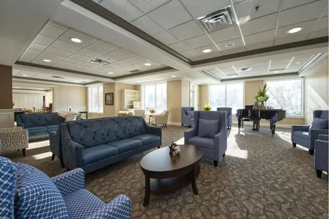 Lounge with upholstered seating, tables and a grand piano.