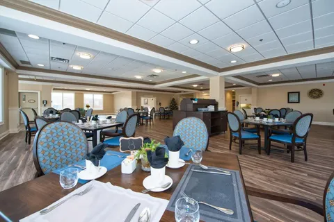 Dining room with set tables, upholstered chairs and large windows.