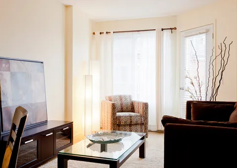 Sitting area with a sofa, armchair, glass table and tall windows