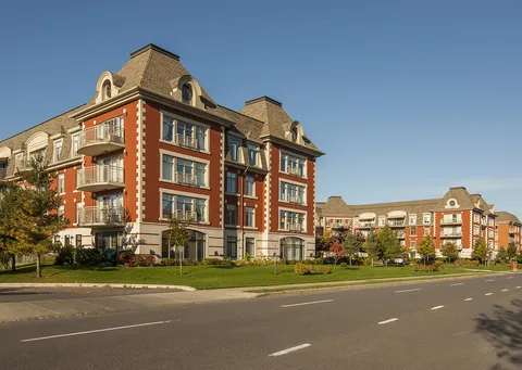Brick residence buildings beside a road and landscaped lawns
