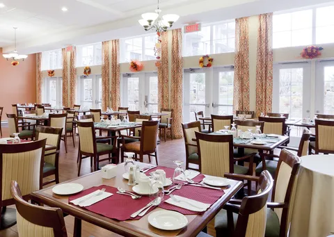 Dining room with set tables and chairs beside tall windows