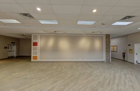 Empty room with wood flooring, wall panels and ceiling lights