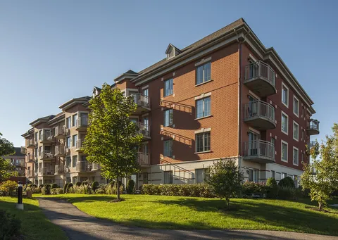Brick residence with balconies beside a lawn and paved path