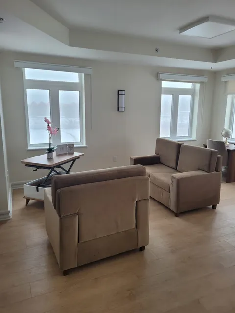 Suite living area with armchairs beside large windows.
